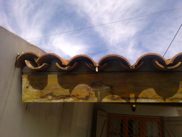 Por falta de mantenimiento,  en techos de tejas coloniales, aquí se ve caída y rota la cenefa del frente del garage